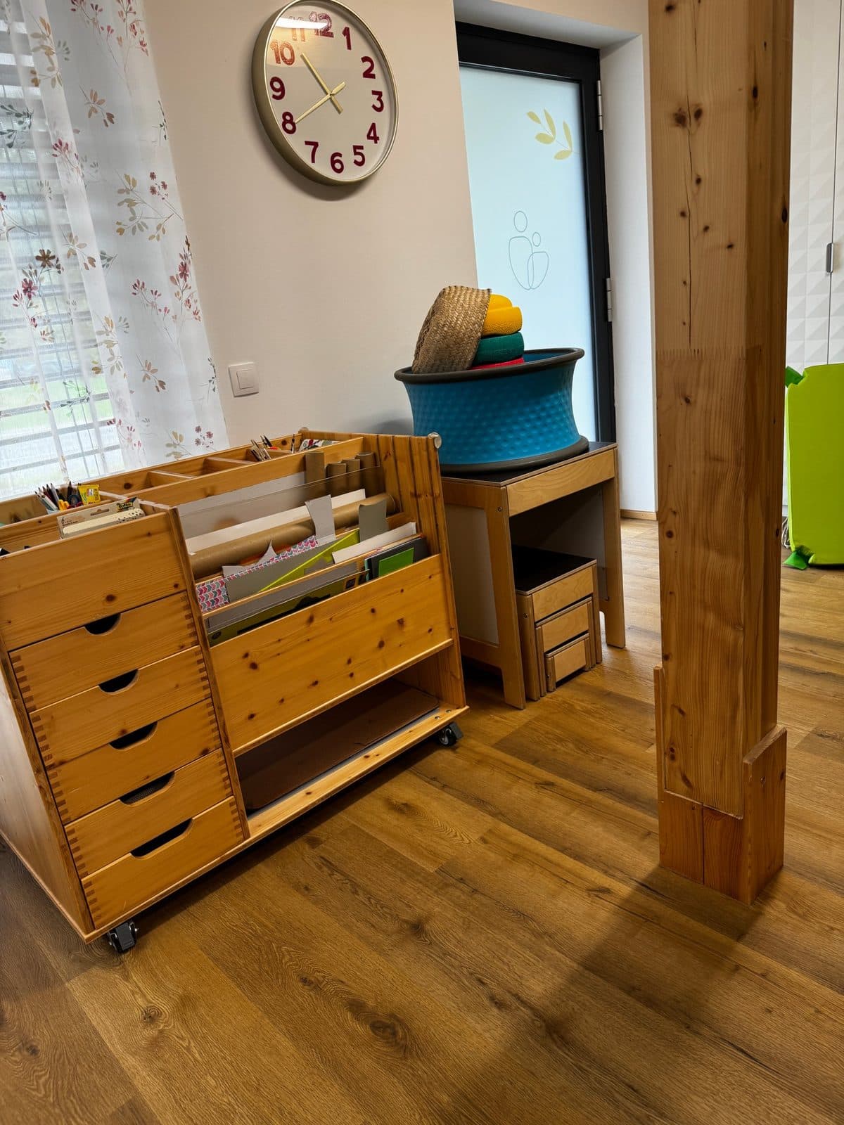 Holzwagen mit Papier, Stiften und Bastelmaterial, dahinter Wanne mit Balancierkissen