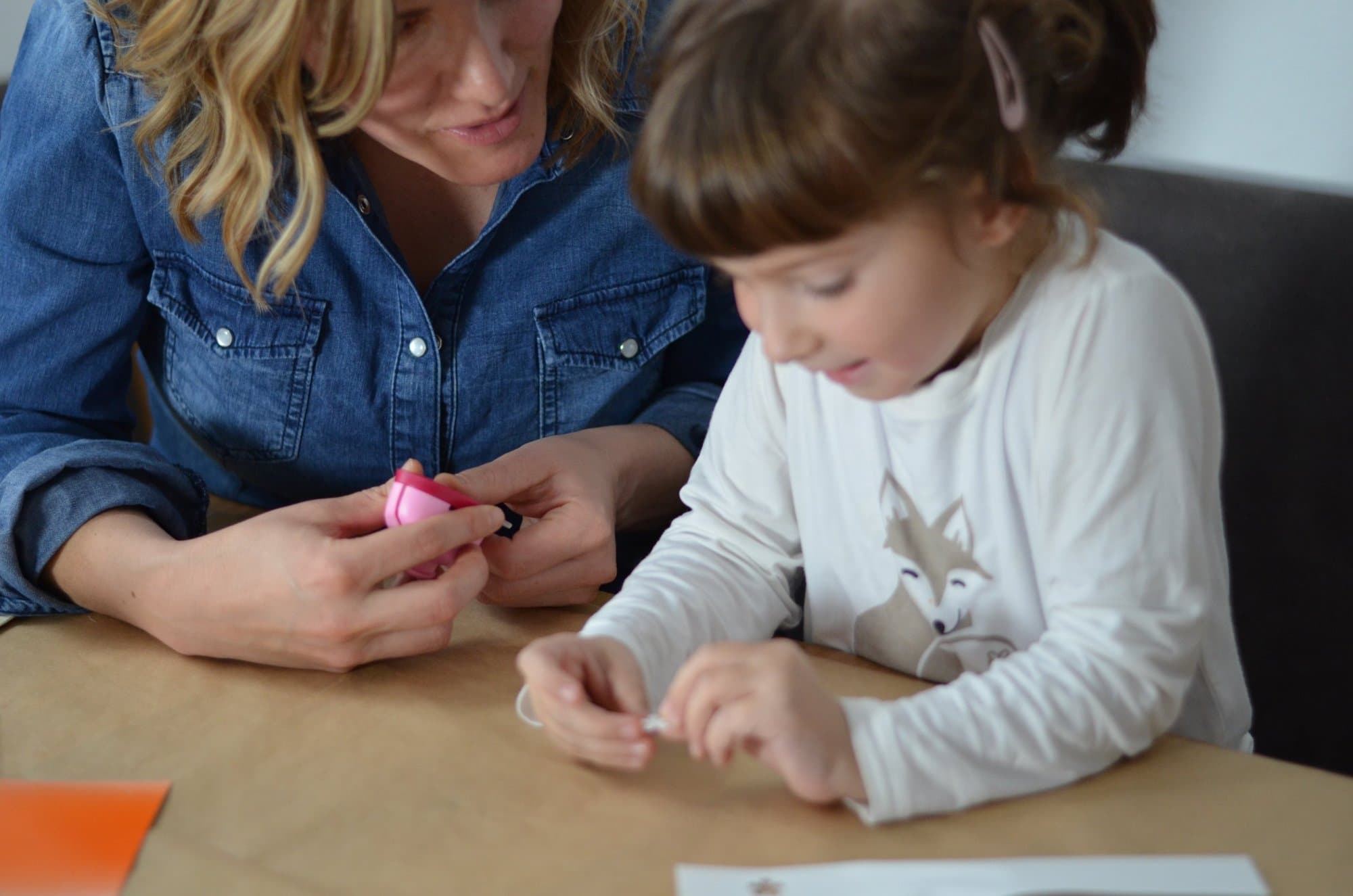 Lisa Lugger Breidler und ein Mädchen arbeiten am Tisch mit kleinen Teilen und Schnüren